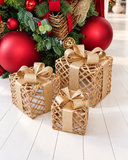 Trio Trama Dourada, caixas decorativas de Natal em forma de presente, com trançado aberto em tom natural e laço em fita dourada.
