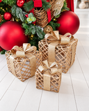 Trio de caixas decorativas de Natal Trama Dourada em três tamanhos, com estrutura em trama vazada natural e laço largo em fita dourada brilhante.