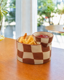 Pote de cerâmica para batata frita Eat Me xadrez ocre e creme com molheira, servido com batatas e ketchup sobre mesa de madeira