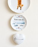 Detalhe da composição de parede com prato decorativo e o coração Compasso do Amor em porcelana branca