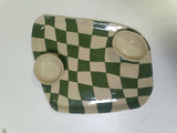 Petisqueira de cerâmica Oval Chess em xadrez verde e off-white com duas cumbucas, sobre superfície branca, destacando o brilho do esmalte.